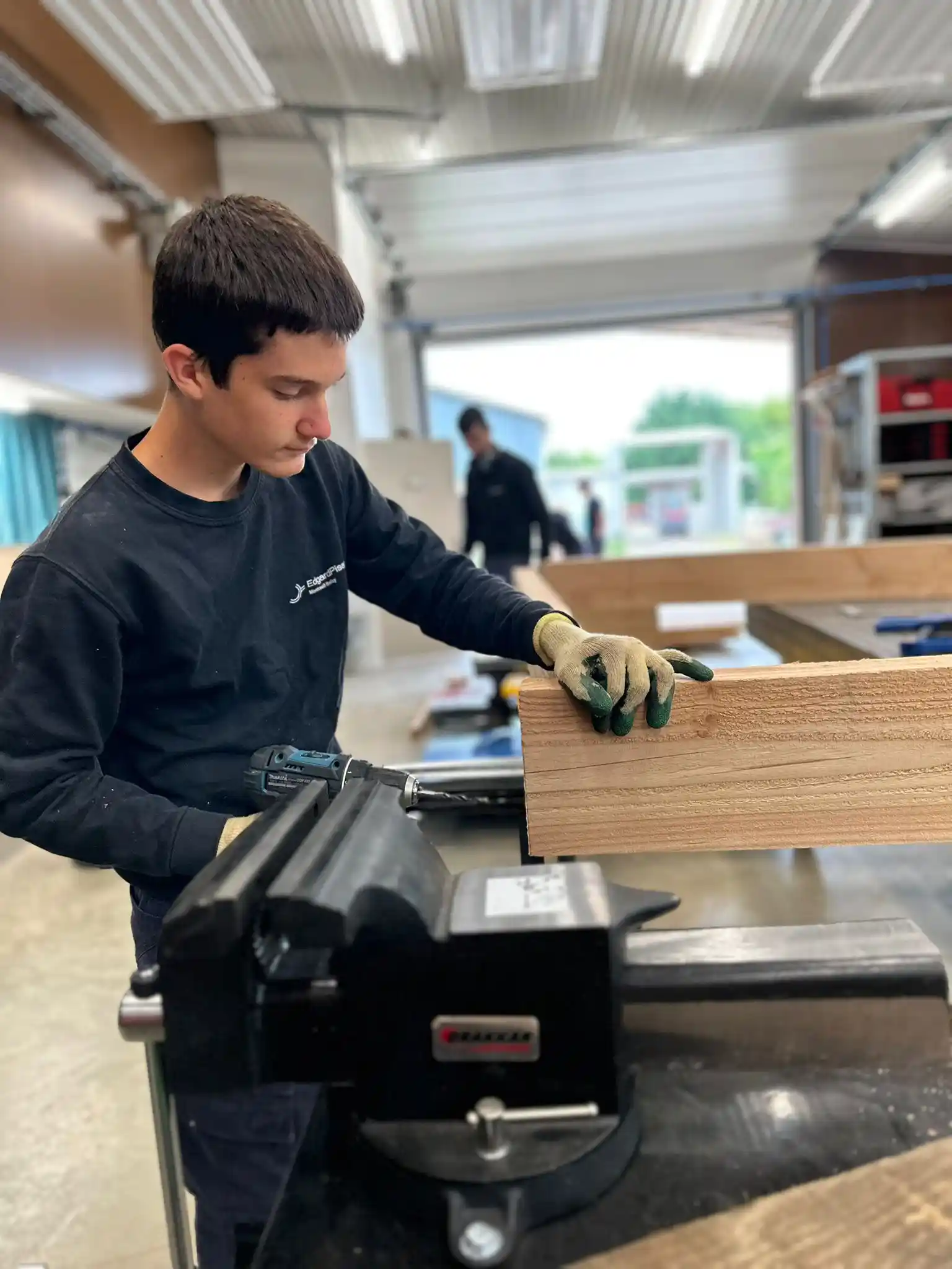 Apprenant travaillant une planche de bois à l'établi