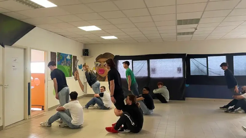 Apprenants assis au sol pendant un exercice, dans une salle d'activité