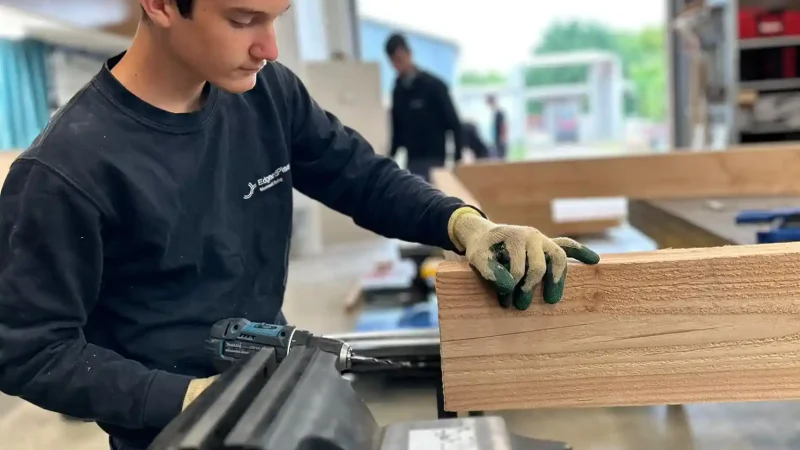 Apprenant travaillant une planche de bois à l'établi